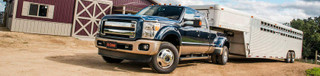 Heavy-duty commercial truck utilizing an underbed CURT gooseneck hitch system to safely tow a loaded flatbed trailer